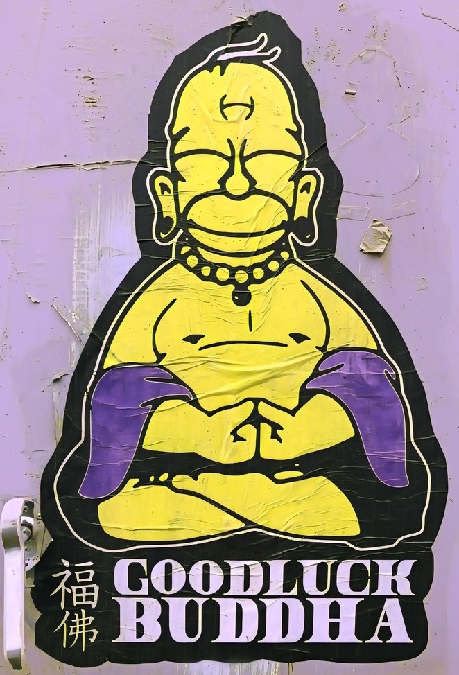 Photo of a sticker on a wall featuring Homer Simpson as "Good Luck Buddha"